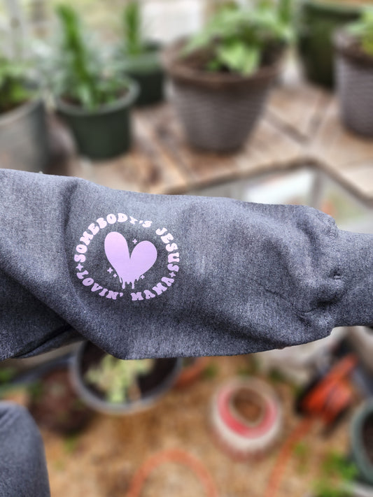Jesus Hoodie with pink writting of, Sombody's Jesus Lovin Mama with a pink heart in the middle on the sleeve