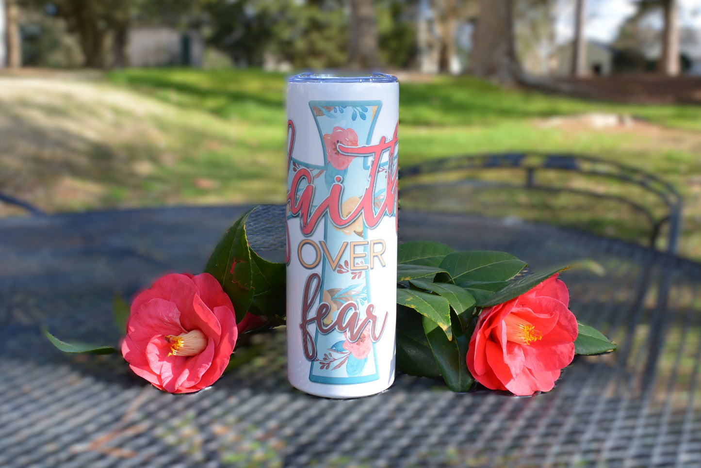 20 oz tumbler with the message faith over fear, with a cross behind it. Christian tumbler